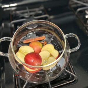 A simmer pot on the stove with the ingredients to make a homemade potpourri recipe for warm apple spice.