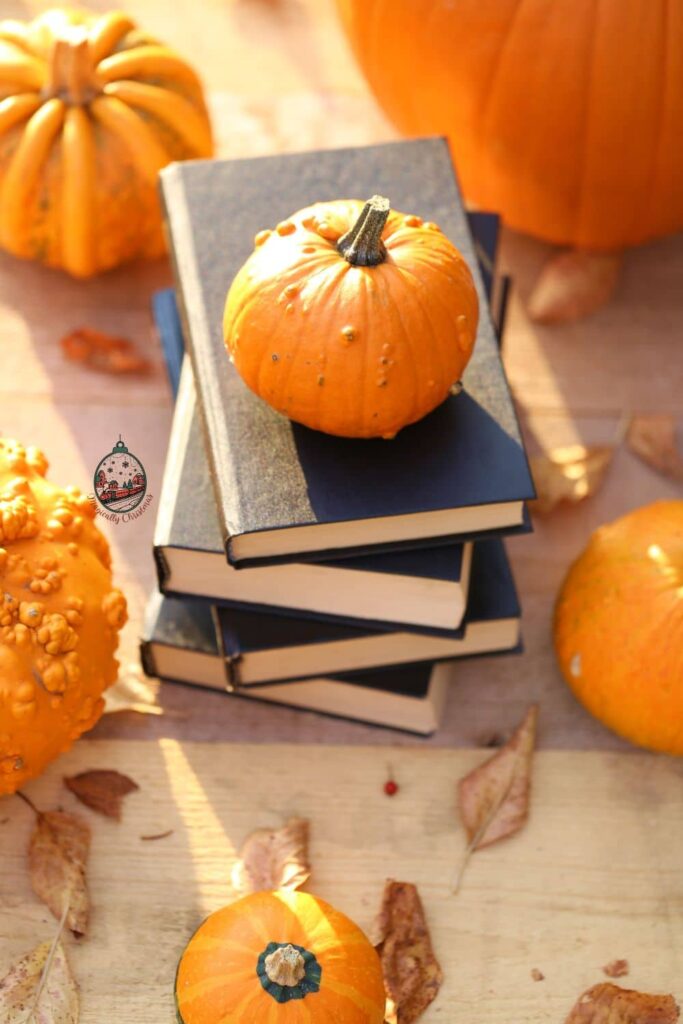 Small pumpkins on and around a stack of books.