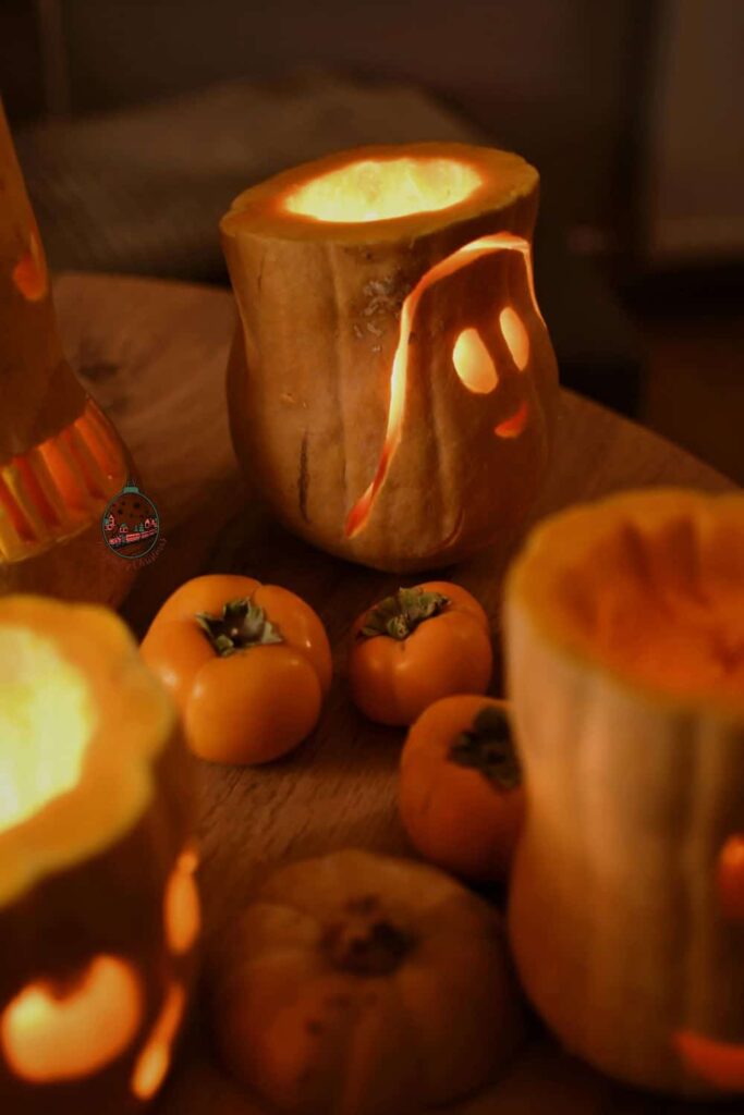 Gourdes that are carved and have candles that are in them and lit up.
