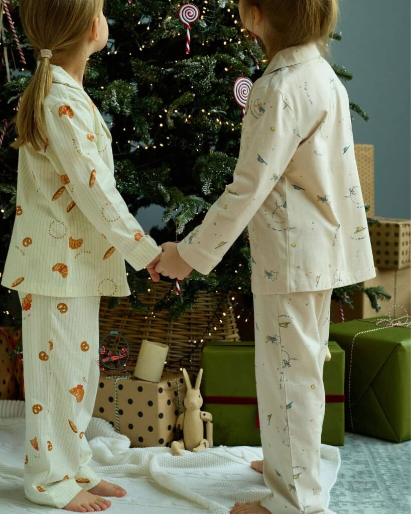 Kids in Christmas pajamas in front of a Christmas tree.