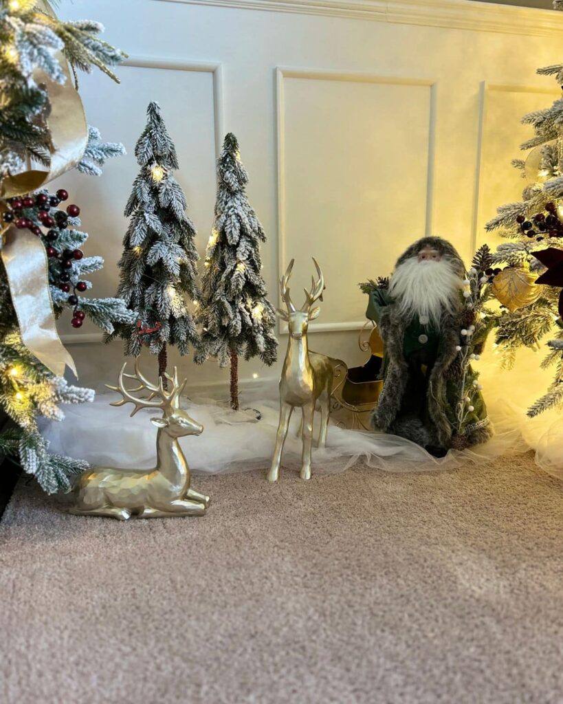 Christmas decorations of tree, Santa, and two reindeer on a floor.