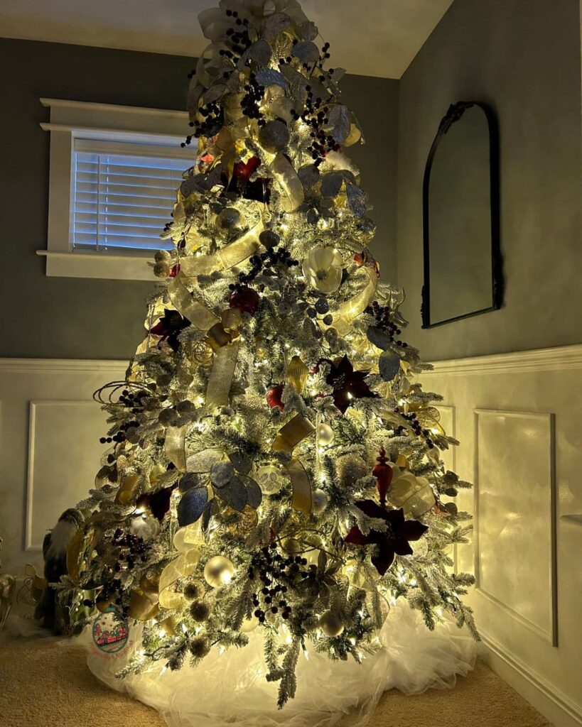 A flocked CHristmas tree in a living room at night all lit up.