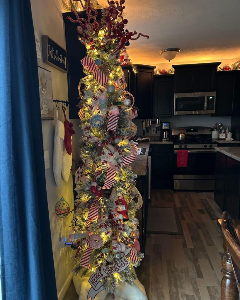 A pencil Christmas tree in a kitchen that is fully decorated for the season.