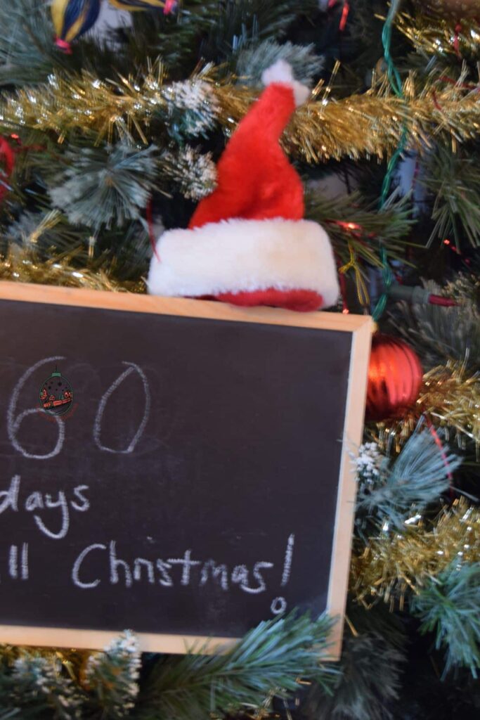 Rustic chalkboard Christmas countdown sign in front of a decorated Christmas tree, perfect for holiday home decor and festive traditions.