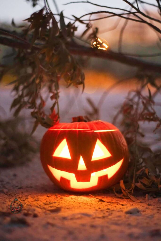 A happily glowing carved pumpkin on a beach.